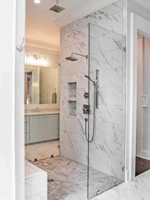 This his & her walk-in shower has a tall piece of clear glass on either side, but no door -- as seen in a collection of master bathrooms.