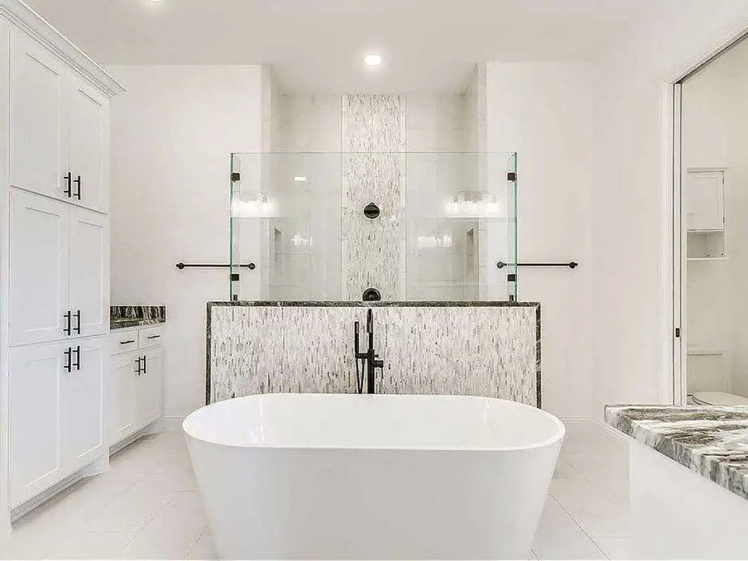 This is a super classy walk-thru shower for a master bathroom featuring a half-glass wall as the divider that separates the shower form the rest of the room -- as seen in a house for sale.